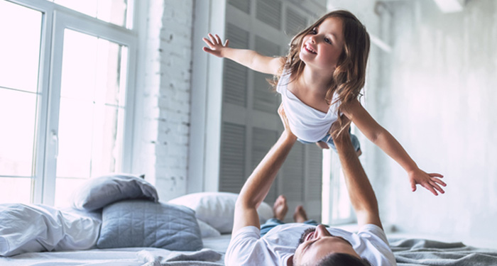 Dad holding young daughter up above him